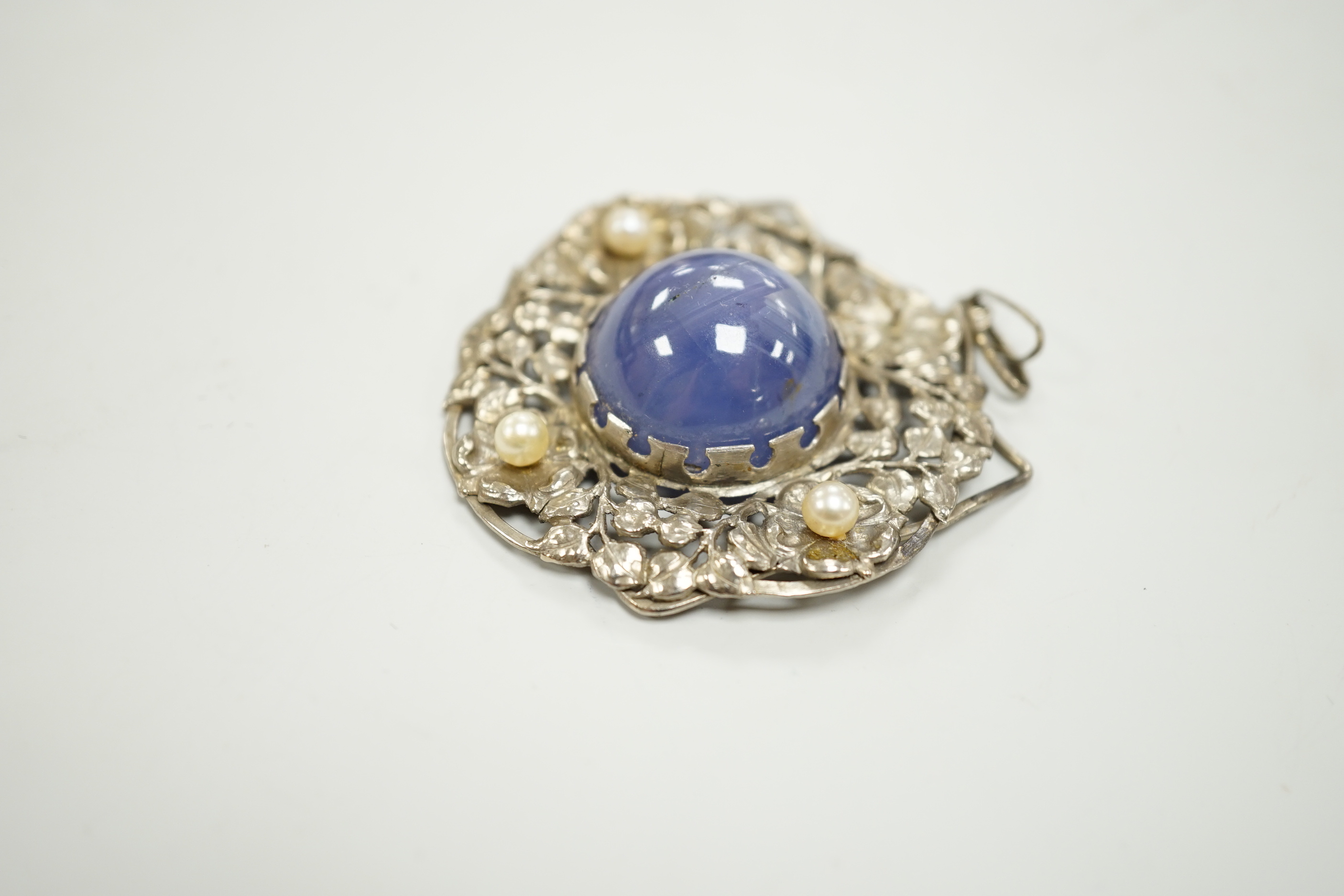 An early 20th century continental pierced white metal, cabochon star sapphire and cultured pearl set circular pendant, diameter 46mm.
